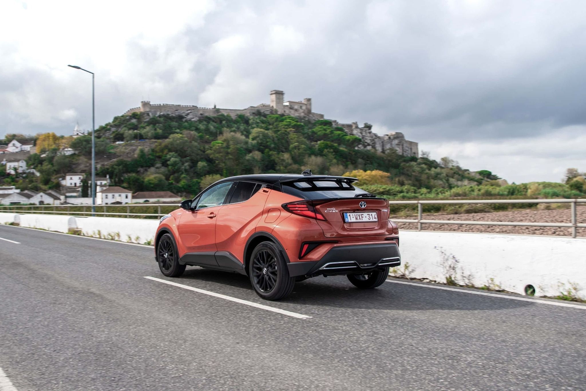 orange and black 2020 toyota c-hr driving past a castle