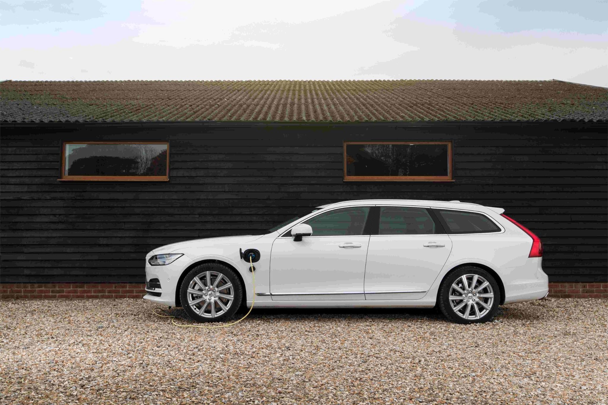 side of white volvo v90 at a charging point