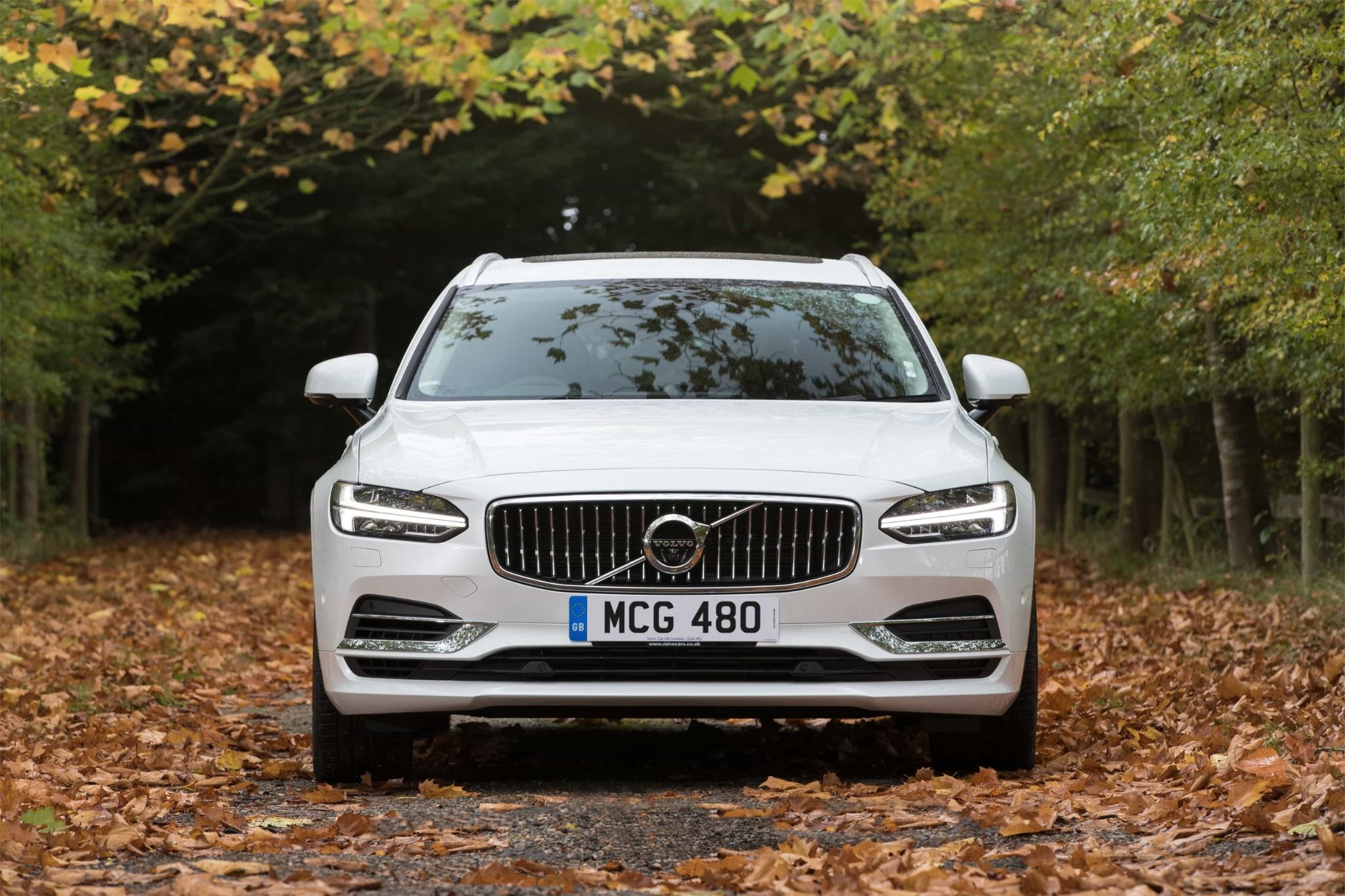 front of white volvo v90 on a country road