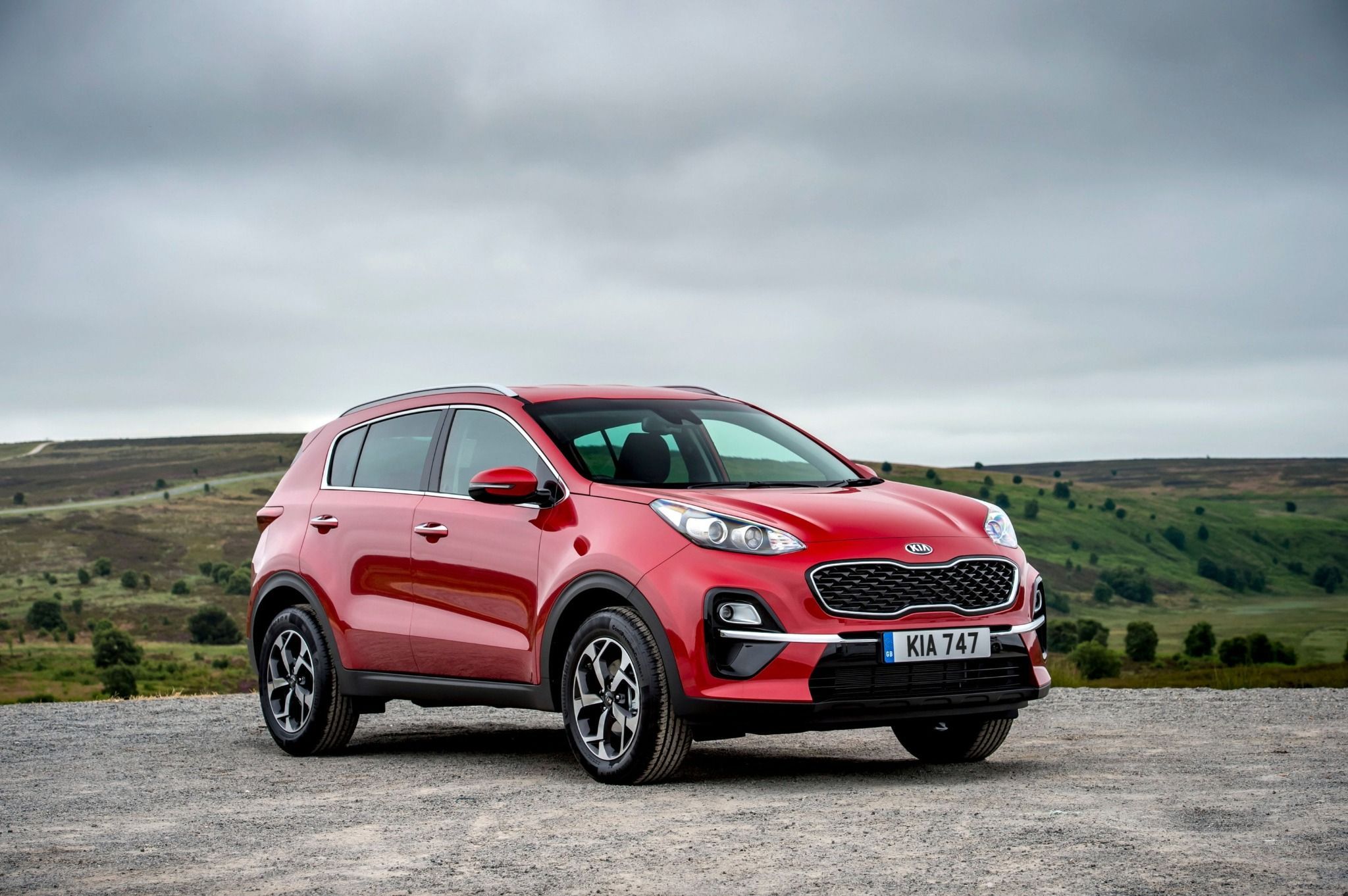 side front view of red kia sportage on country road