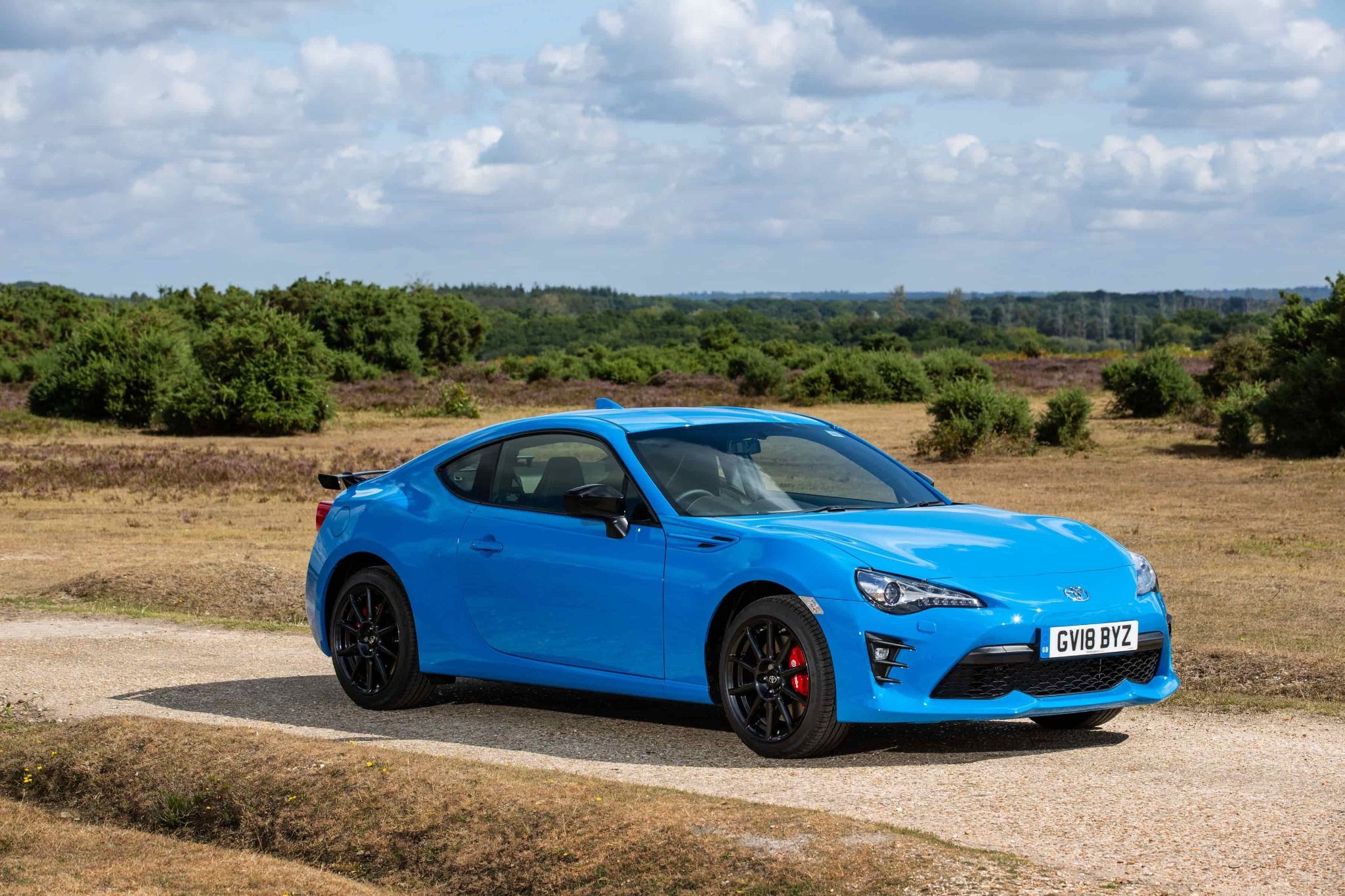blue toyota gt86 parked in front of fields and trees