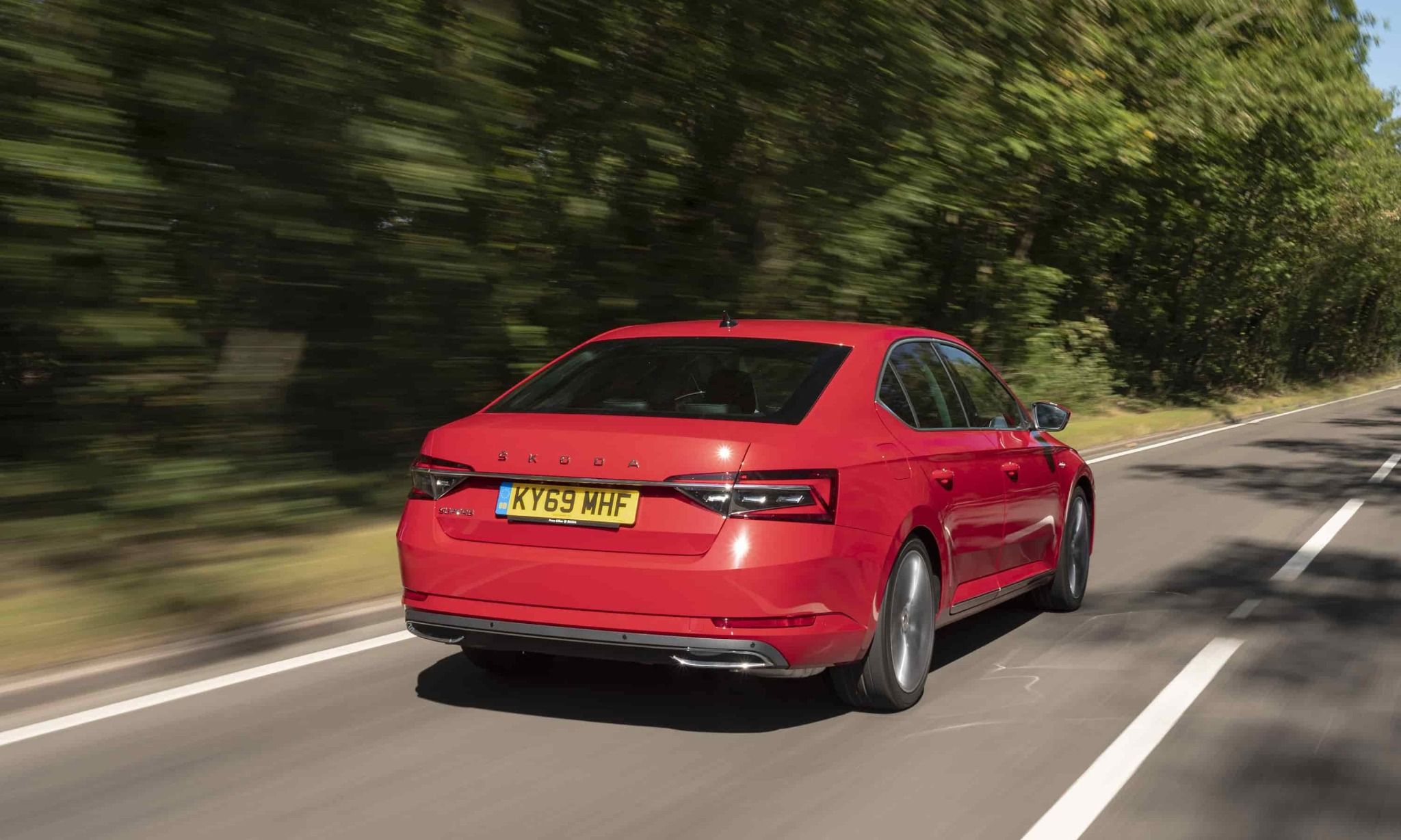 rear view of red skoda driving along a road