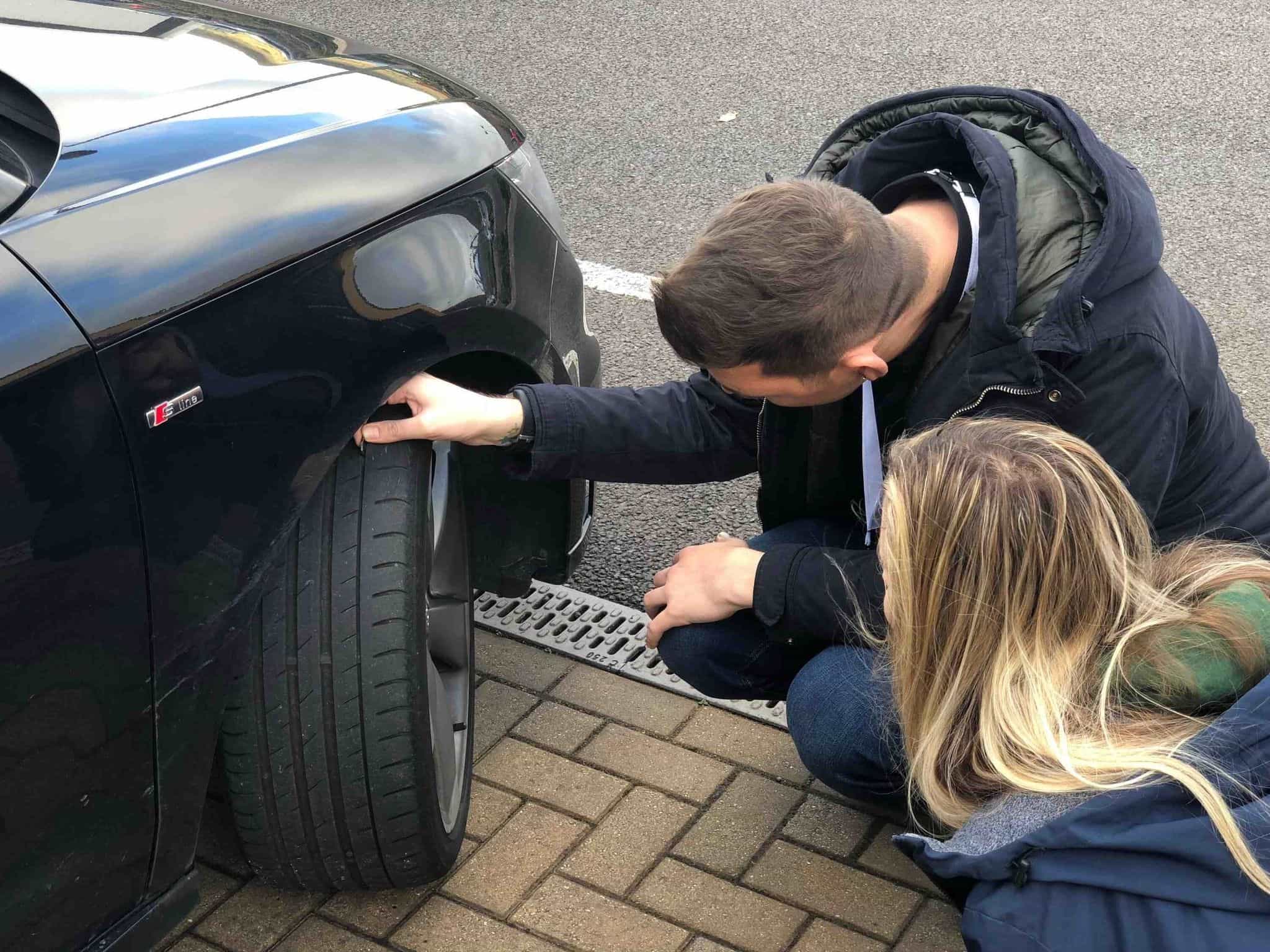 man and woman checking the tyre on a car