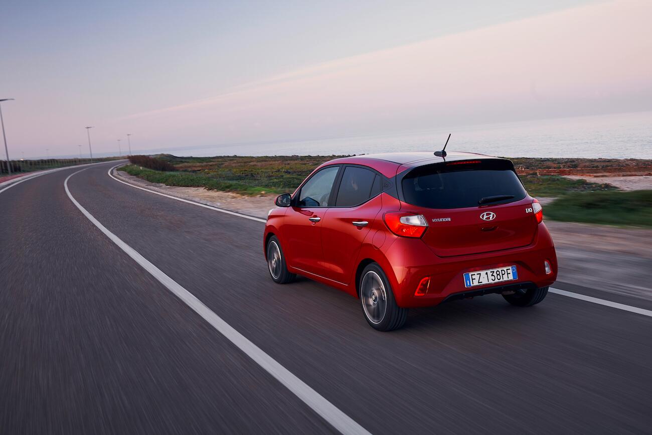 Red car driving down road