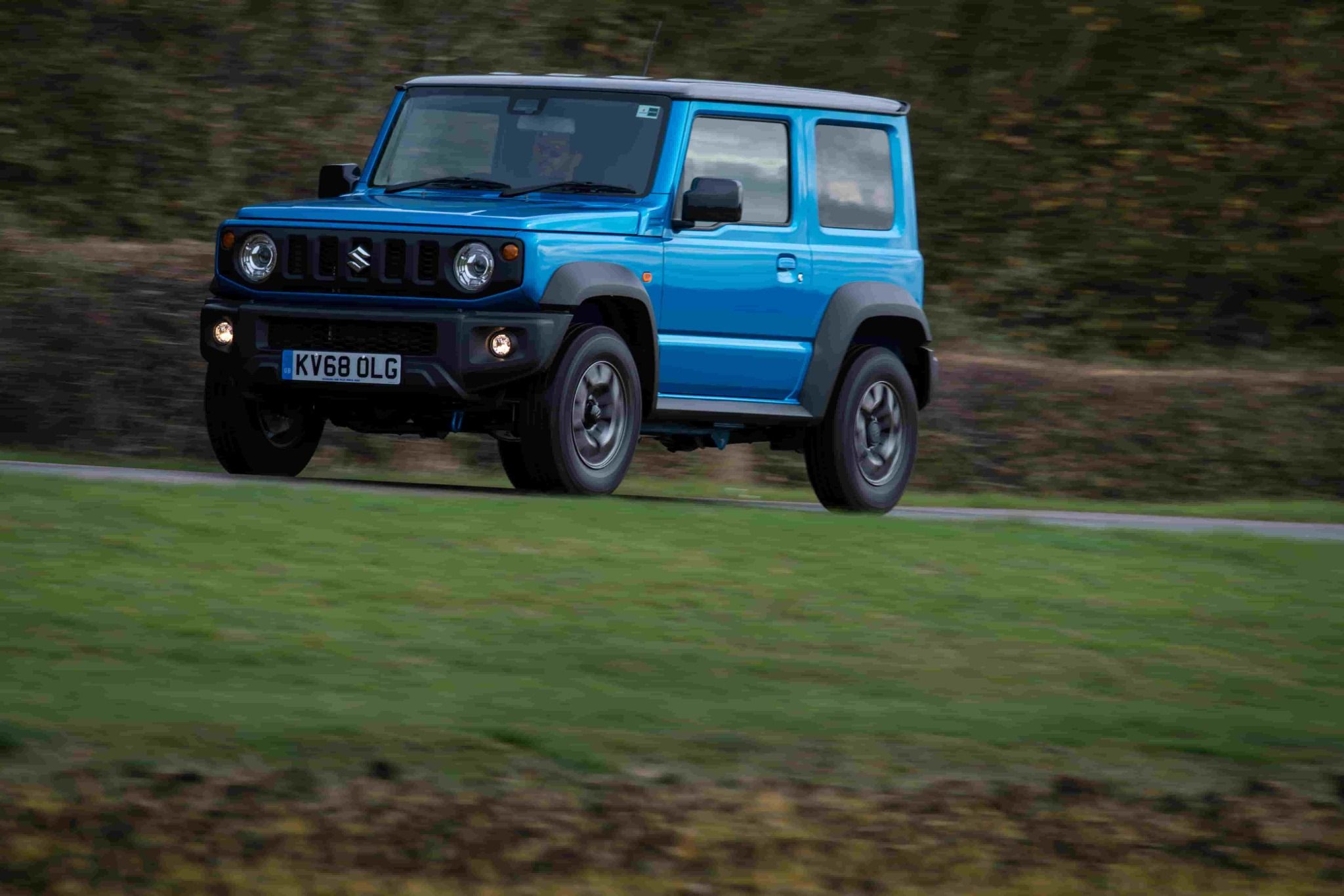 Blue suzuki jimny driving on grass
