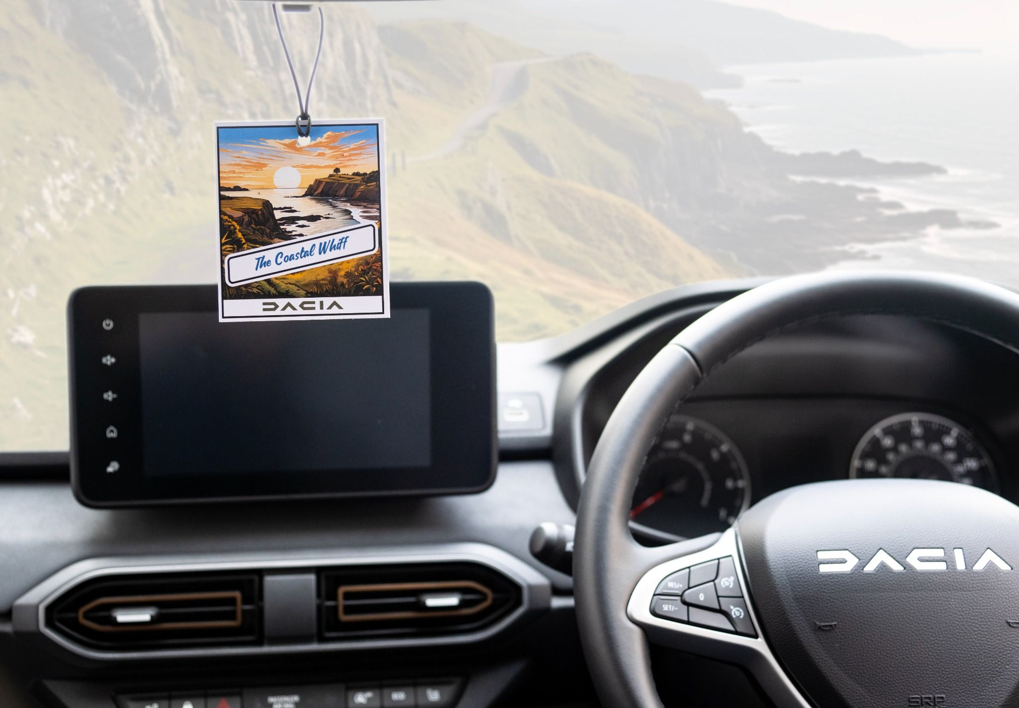 Dacia air freshener: the costal whiff, handing in a car with a view of a coastline.
