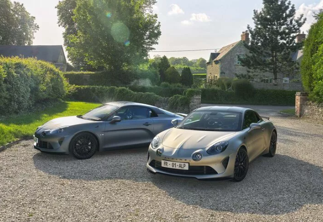 The Alpine A110 S Enstone Edition. Two cars on a country driveway.