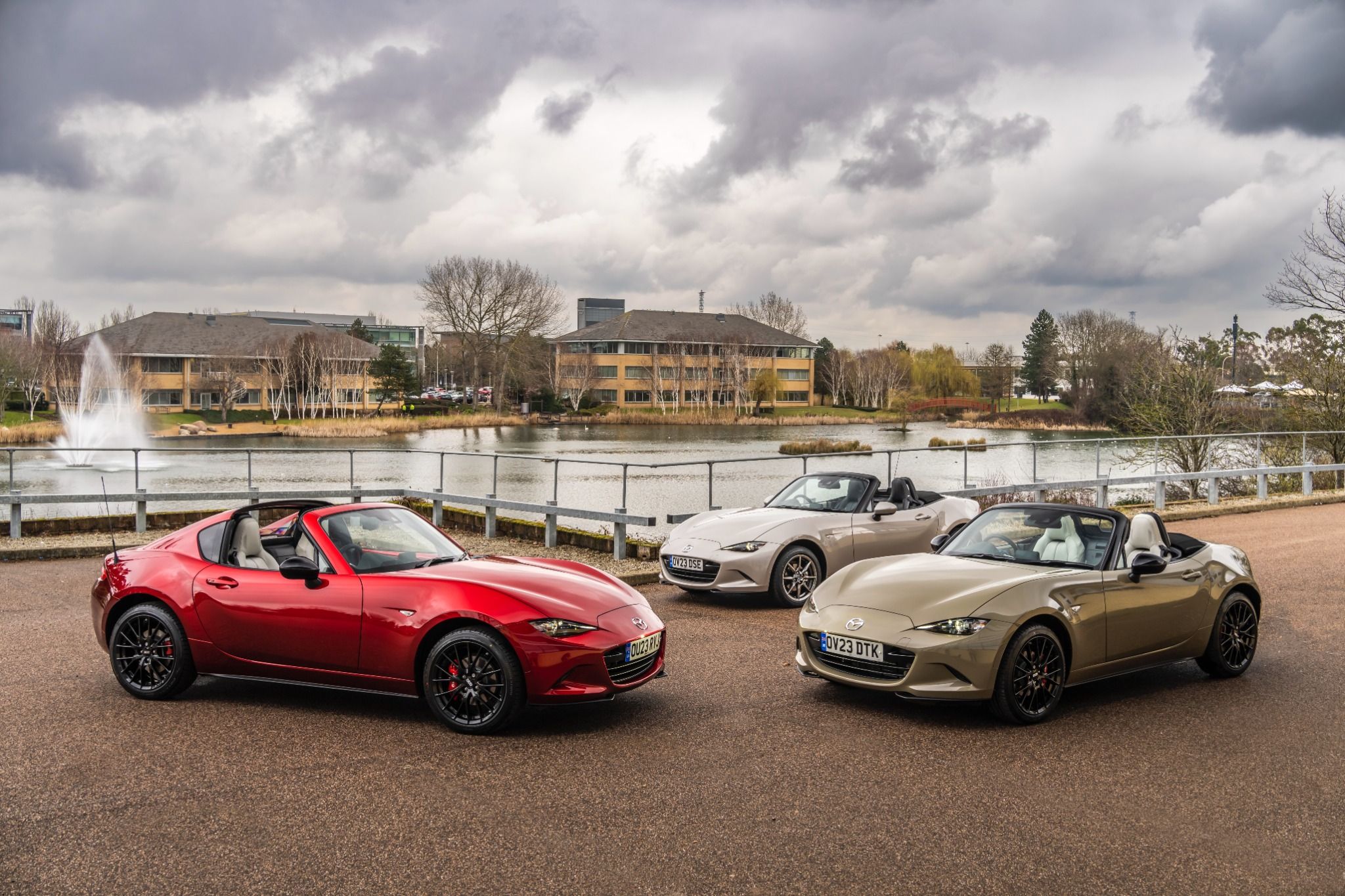 Three Mazda MX-5 parked by a lake