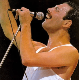 Freddie Mercury from Queen singing into a micrphone with his eyes closed and one arm raised
