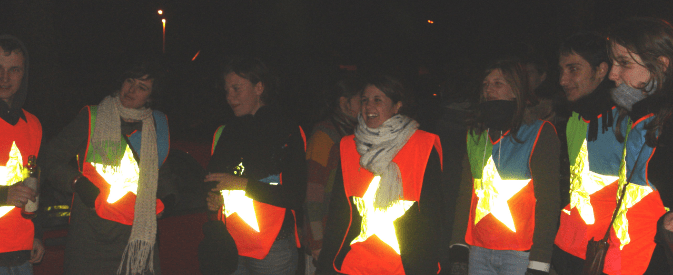 Group of people in the dark with orange hi visibility vests with stars on