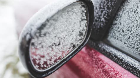 Red car wing mirror frozen in the ice and snow